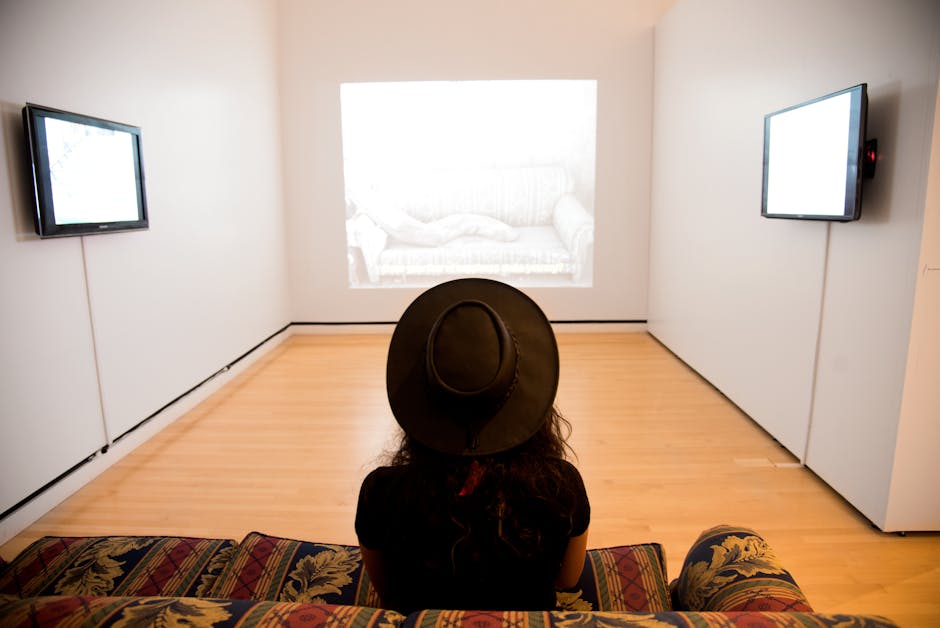 A person with a hat views an art installation in a minimalist gallery space.