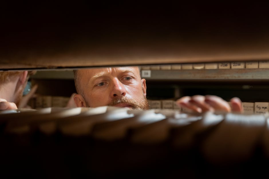 A man searches through archives in an office storage room, focused and working.