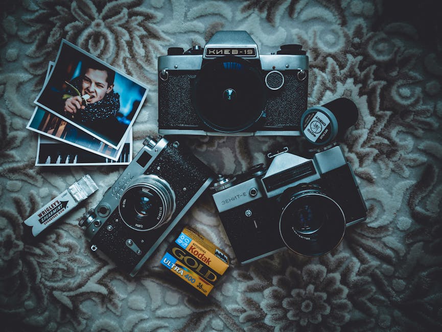 Flat lay of vintage film cameras, photographic film, and prints on a patterned background.