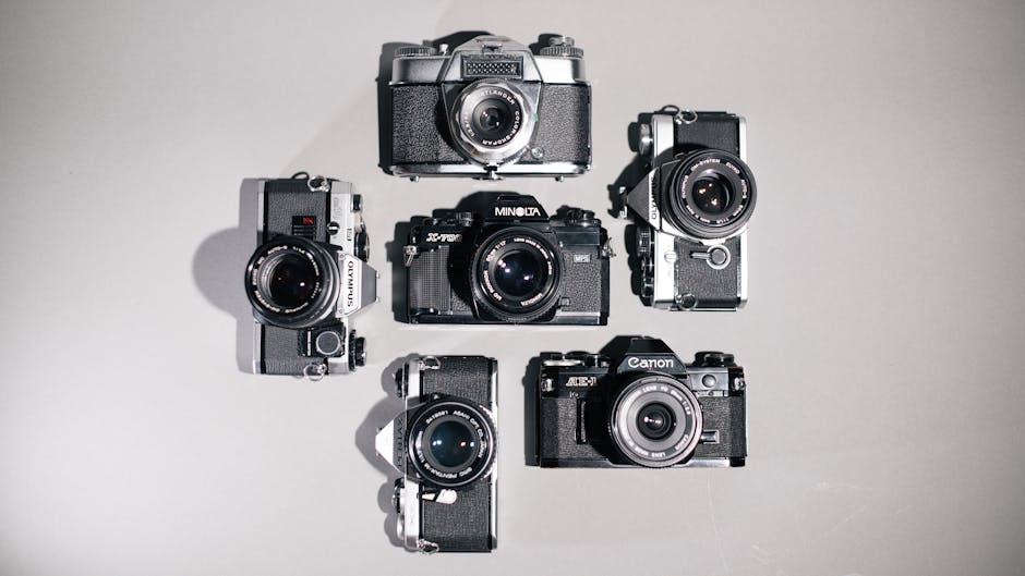 Flat lay of vintage analog cameras arranged on a neutral surface.