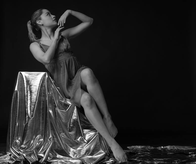 Elegant black and white portrait of a ballet dancer posing gracefully against a metallic backdrop.